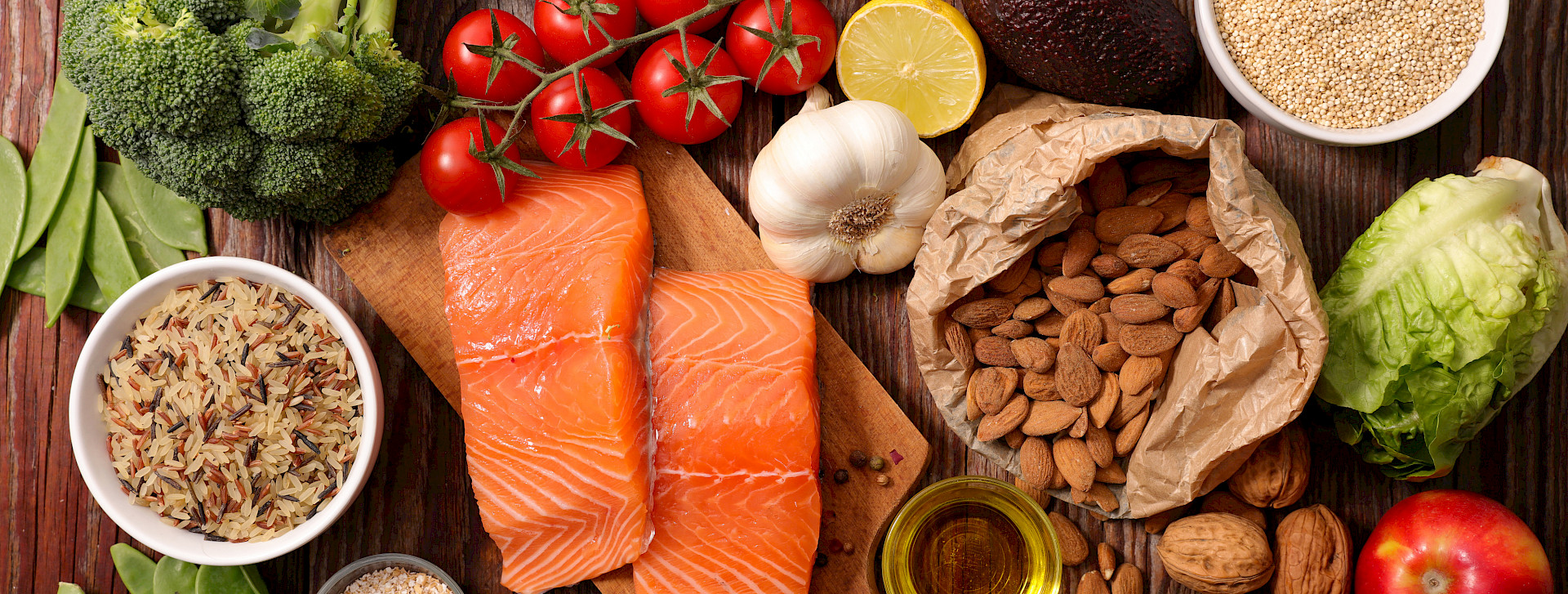 Various foods (fish, nuts, fruits and vegetables) on a wooden table