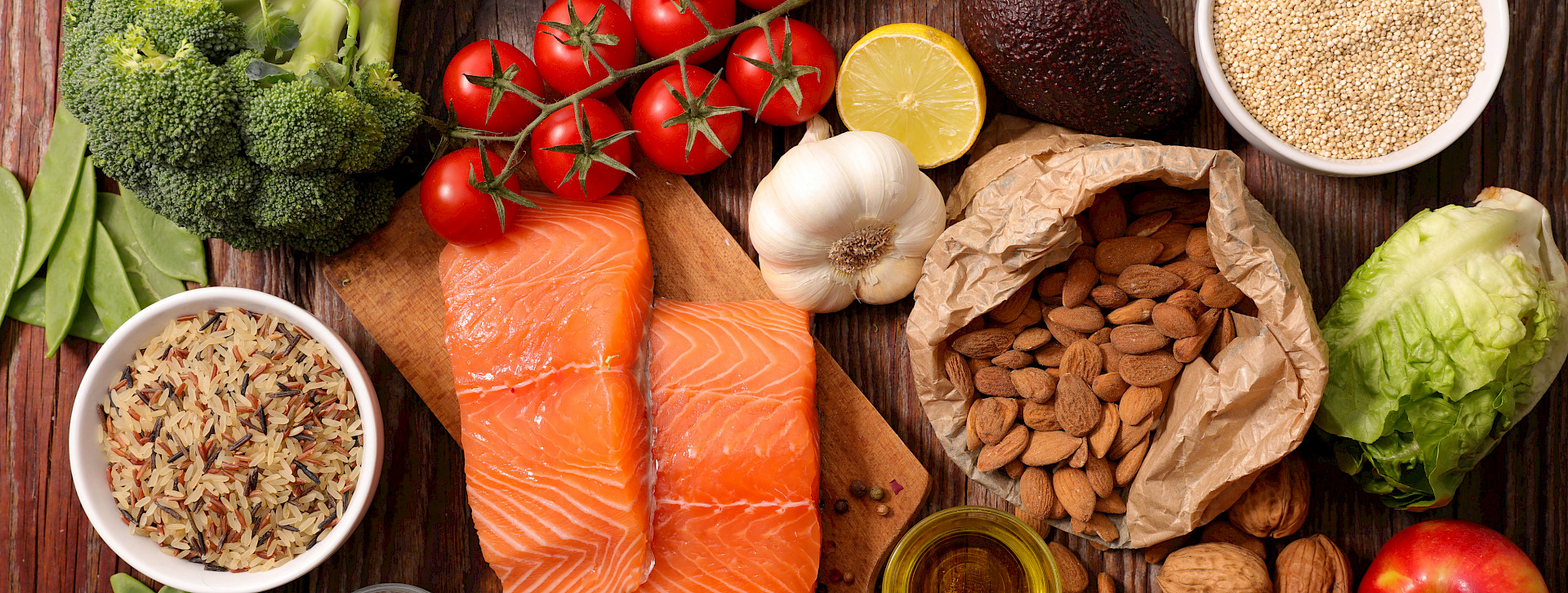 Various foods (fish, nuts, fruits and vegetables) on a wooden table