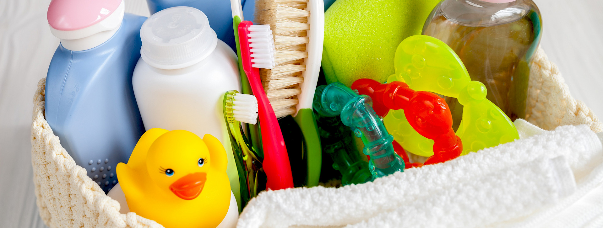 Verschiedene Bedarfsgegenstände in einem Korb (Shampoo, Zahnbürste, Spielzeug)
