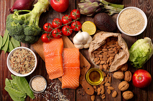 Verschiedene Lebensmittel (Fisch, Nüsse, Obst und Gemüse) auf einem Holztisch