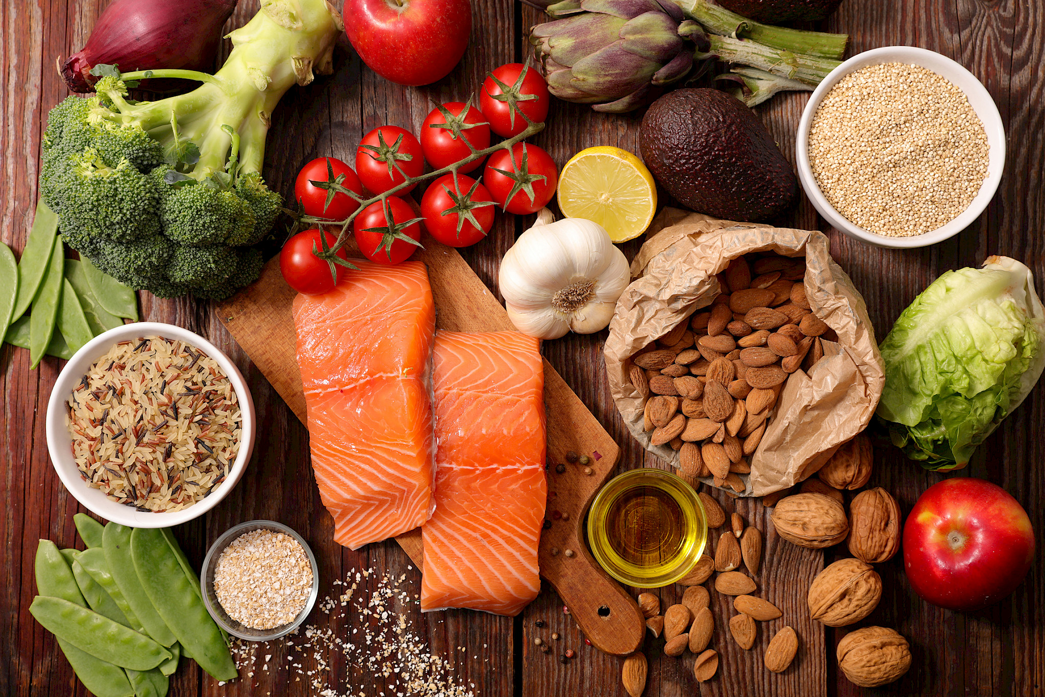 Various foods (fish, nuts, fruits and vegetables) on a wooden table